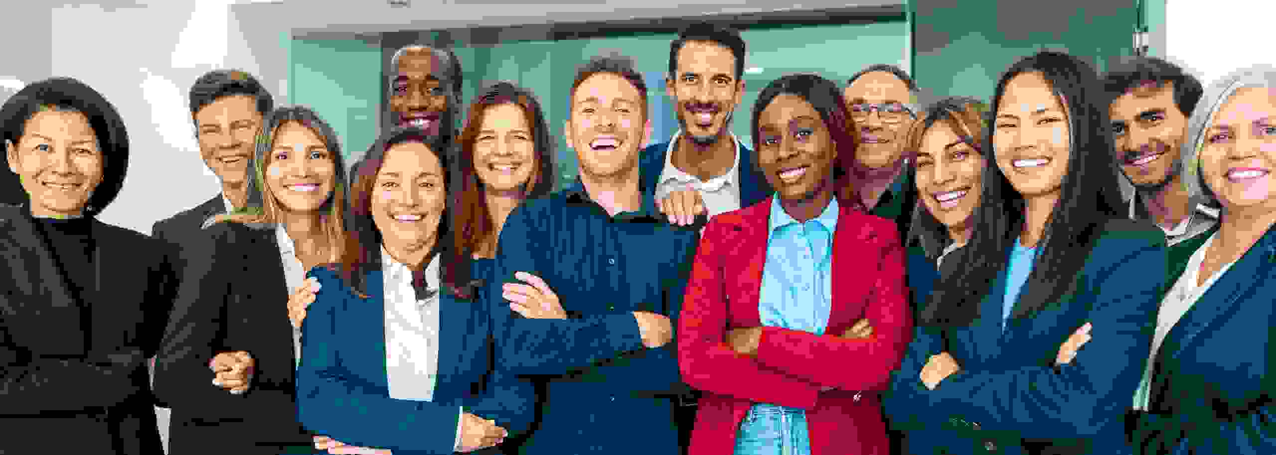 Gruppenfoto von lächelnden Mitarbeitern verschiedener Ethnien in formeller Kleidung.