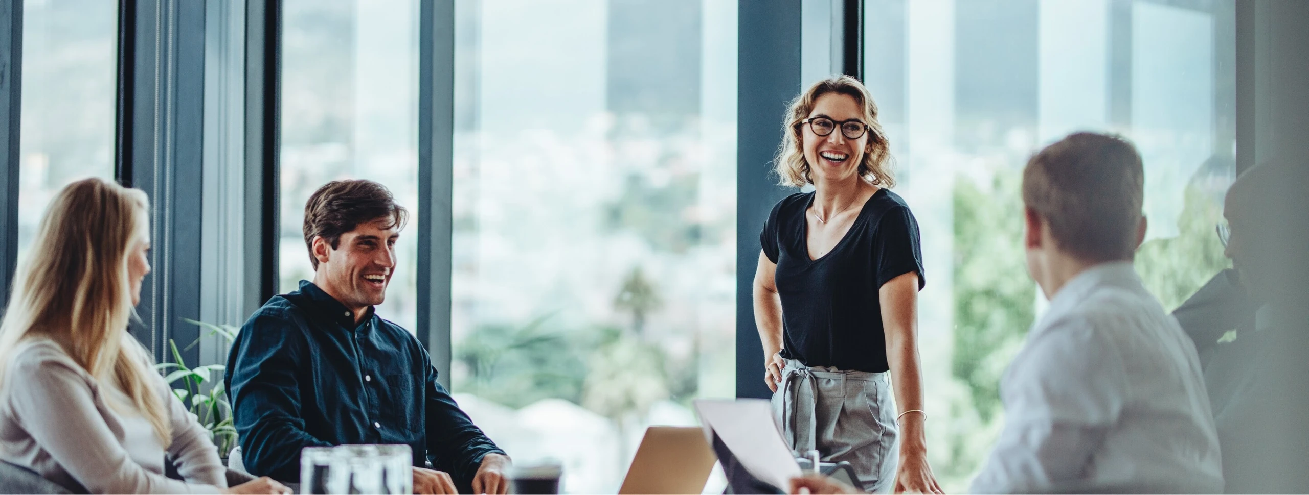Fünf Menschen bei guter Laune in einem verglasten Meetingraum