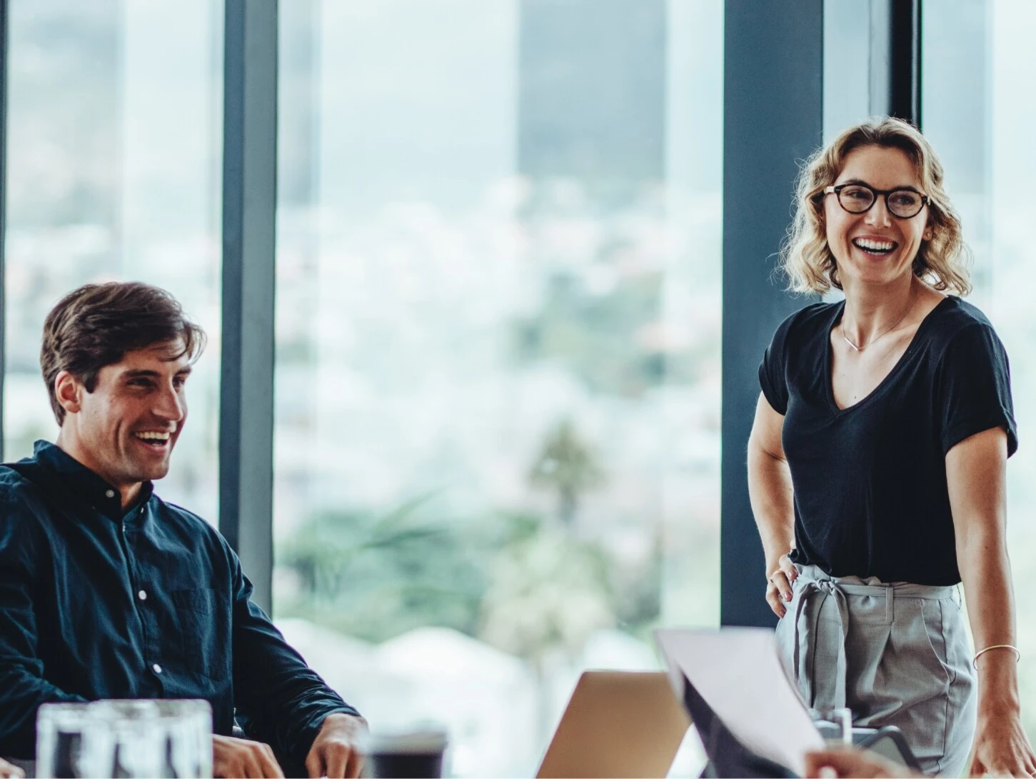 Fünf Menschen bei guter Laune in einem verglasten Meetingraum