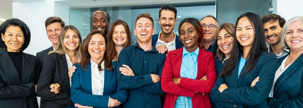 Gruppenfoto von lächelnden Mitarbeitern verschiedener Ethnien in formeller Kleidung.